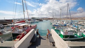 Un port de plaisance avec des bateaux amarrés, un escalier en bois menant à l’eau et un ciel dégagé.