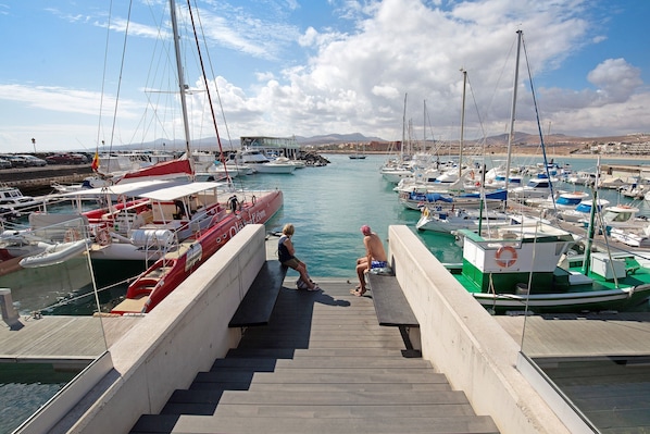 Un port de plaisance avec des bateaux amarrés, un escalier en bois menant à l  ’eau et un ciel dégagé.