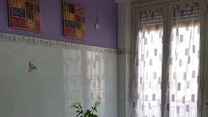 Een eethoek met een tafel, stoelen, een hanglamp en een raam met gordijnen met een patroon.