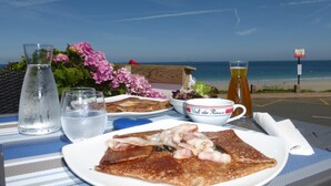 Een ontbijttafel met een bord eten, een glas water, een fles sap en een beker met rietje.