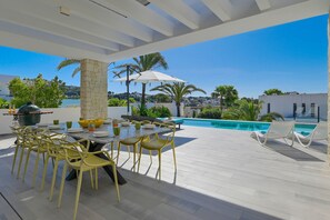 An outdoor patio with a dining table and chairs, a pool, and a view of the surrounding landscape. - Graham Holiday Rentals - Horizon (Moraira)