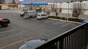 Un estacionamiento con varios vehículos, una gasolinera y montañas al fondo.