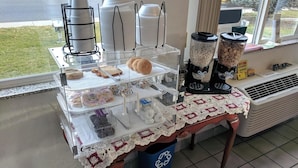 Mostrador de panadería con panes, pasteles y máquinas de café.