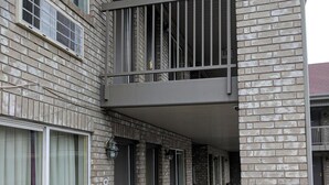 Un edificio de varios pisos de ladrillo con un pórtico, múltiples ventanas y puertas.