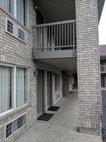 A multi-story brick building with a covered walkway, multiple windows, and doors.