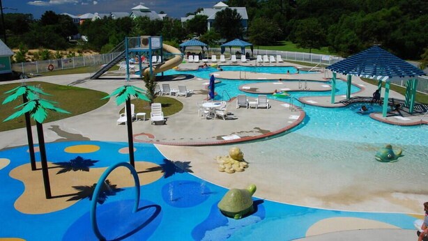 Ein Poolbereich mit Wasserrutschen, Liegestühlen und einer Schildkrötenstatue.