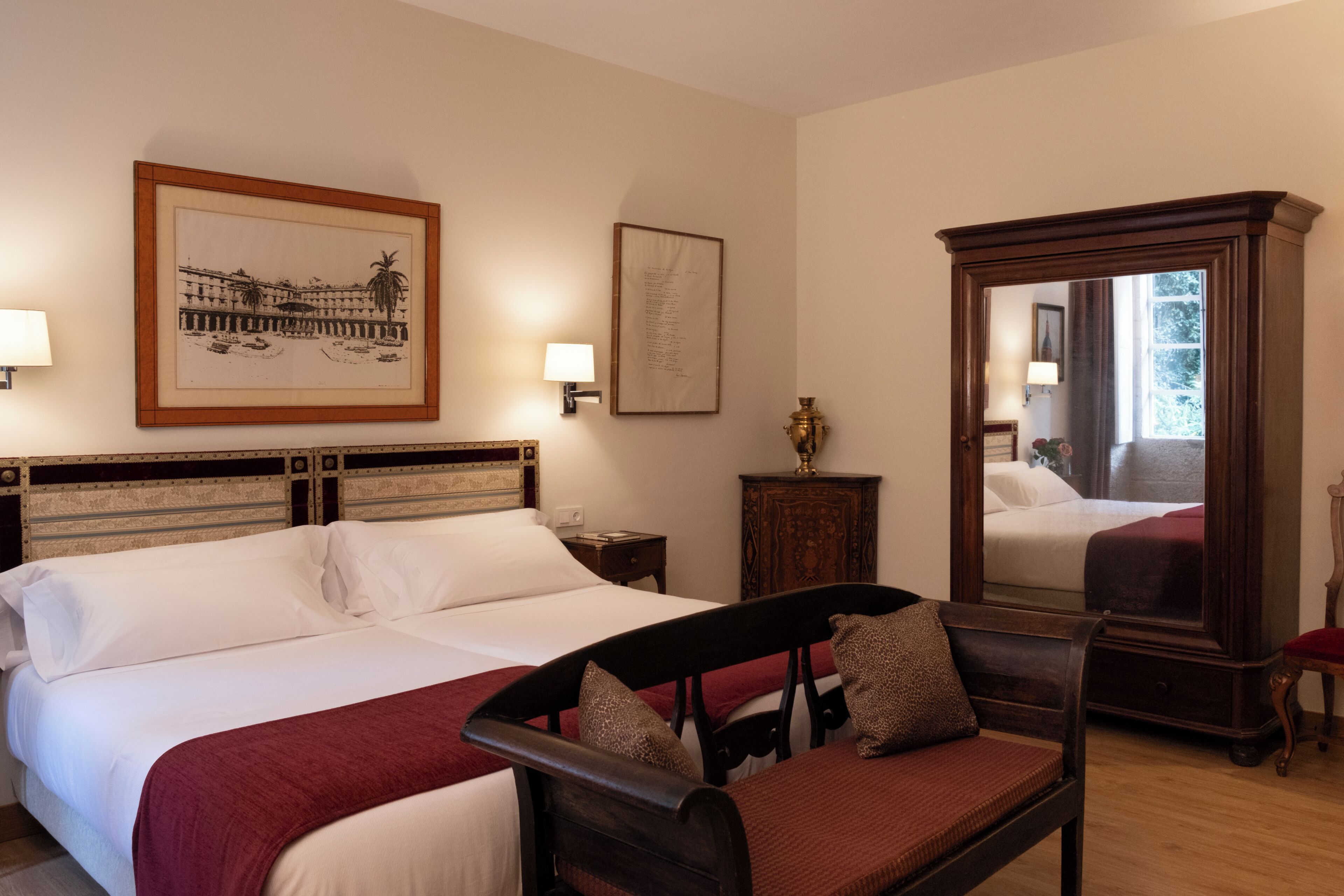 Une chambre d’hôtel avec un lit, une chaise, un miroir et des œuvres d’art accrochées aux murs.