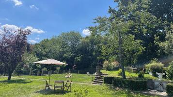 A garden with a table and chairs, a stone fountain, and a tree.