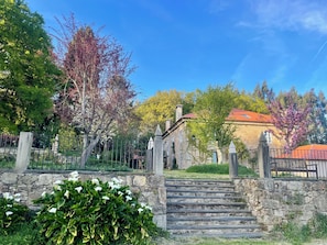 A stone staircase leading to a building with a red-tiled roof, surrounded by greenery and a stone wall. - Hotel Pazo de Bieite (Boimorto)