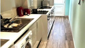 Une cuisine compacte équipée d’un four encastré, d’un four à micro-ondes et d’un lave-linge.