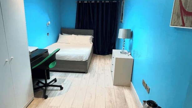 Une pièce de taille modeste comprenant un lit, un bureau, une chaise et une petite kitchenette.
