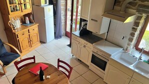 Een keuken met een houten tafel, stoelen en een koelkast.