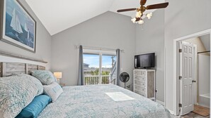 Ein Schlafzimmer mit einem großen Bett, einem Deckenventilator, einem Fernseher und einem Balkon mit Blick.