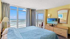 Une chambre d’hôtel avec un grand lit, une télévision, une commode et une vue sur l’océan.