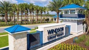 A sign for 'Windsor Island Resort' with a blue roof and white walls, surrounded by palm trees and a clear sky. - 3312 LW 5-BR Luxury Villa with Pool Disney Delight (Four Corners)