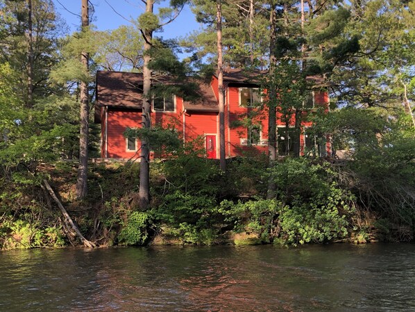 Un edificio rojo rodeado de árboles y un río.
