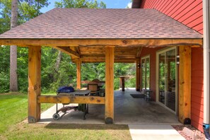 A covered patio with a grill, tables, and chairs. - Amazing River House with covered patio! Sleeps 10-14. Kayaks,Fireplace,Games.  (Colfax)