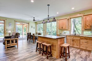 Una cocina amplia con armarios de madera, una isla grande con taburetes y un comedor con sillas.