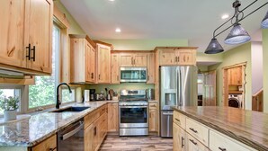 Una cocina con armarios de madera, electrodomésticos de acero inoxidable y encimera de mármol.