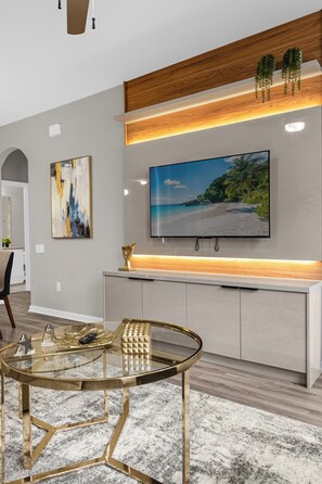 Relax in a stylish space with a large flat-screen TV, glass coffee table, and comfortable seating area.
