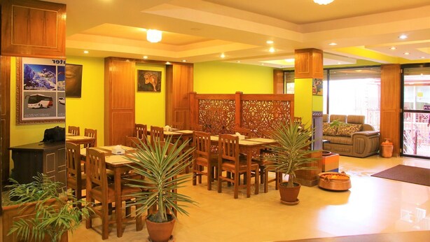 A restaurant with wooden furniture, potted plants, and a bright yellow wall.
