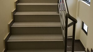 A staircase with a metal handrail and beige steps.