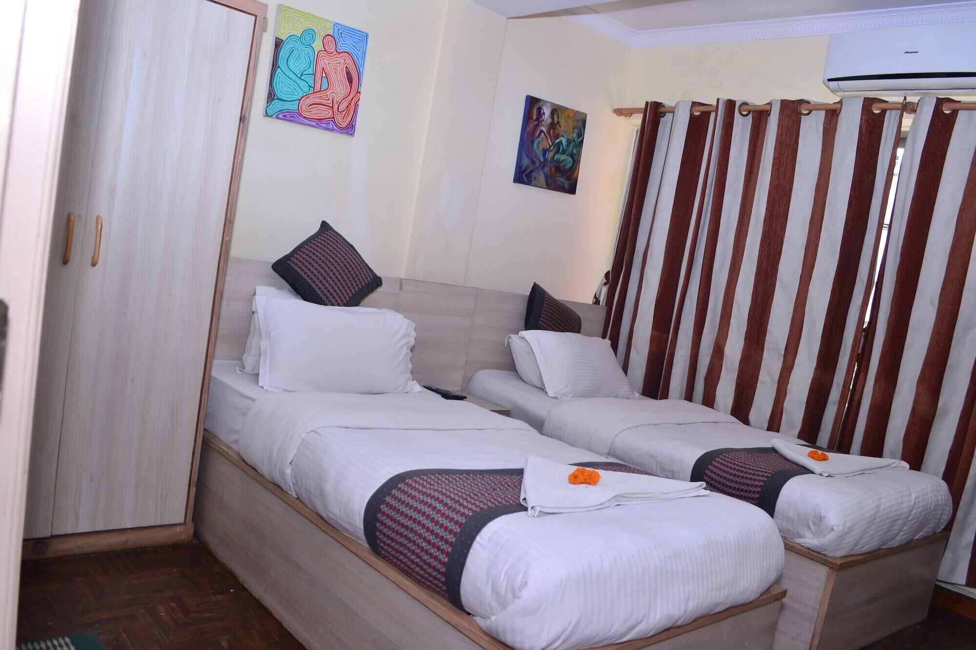 A hotel room with two single beds, a wooden headboard, a painting on the wall, and a window with curtains.