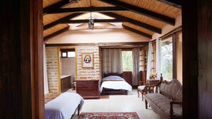 A bedroom with two beds, a wooden bench, and a large window.