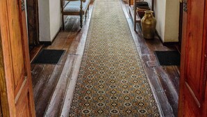 A hallway with wooden floors, a patterned rug, and benches.