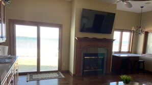 A spacious living room with a fireplace, a television mounted on the wall, and a dining area with a table and chairs.