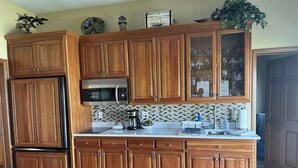 A kitchen with wooden cabinets, a stainless steel microwave, and a tiled backsplash.
