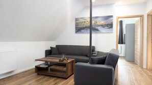 A modern living room with a grey sofa, a wooden coffee table, and a painting on the wall.