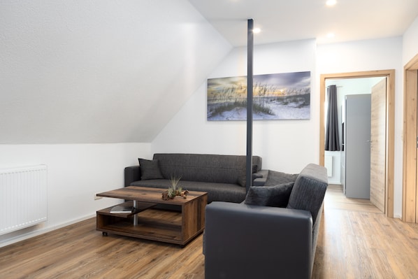 A modern living room with a grey sofa, a wooden coffee table, and a painting on the wall.