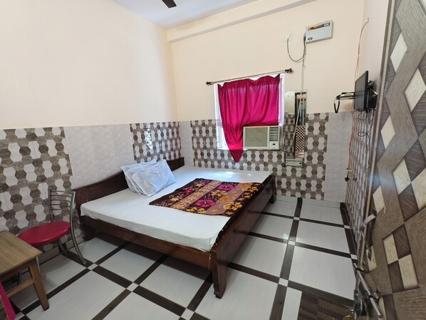 Une chambre à coucher avec un lit, une chaise, un bureau et une fenêtre avec un rideau.