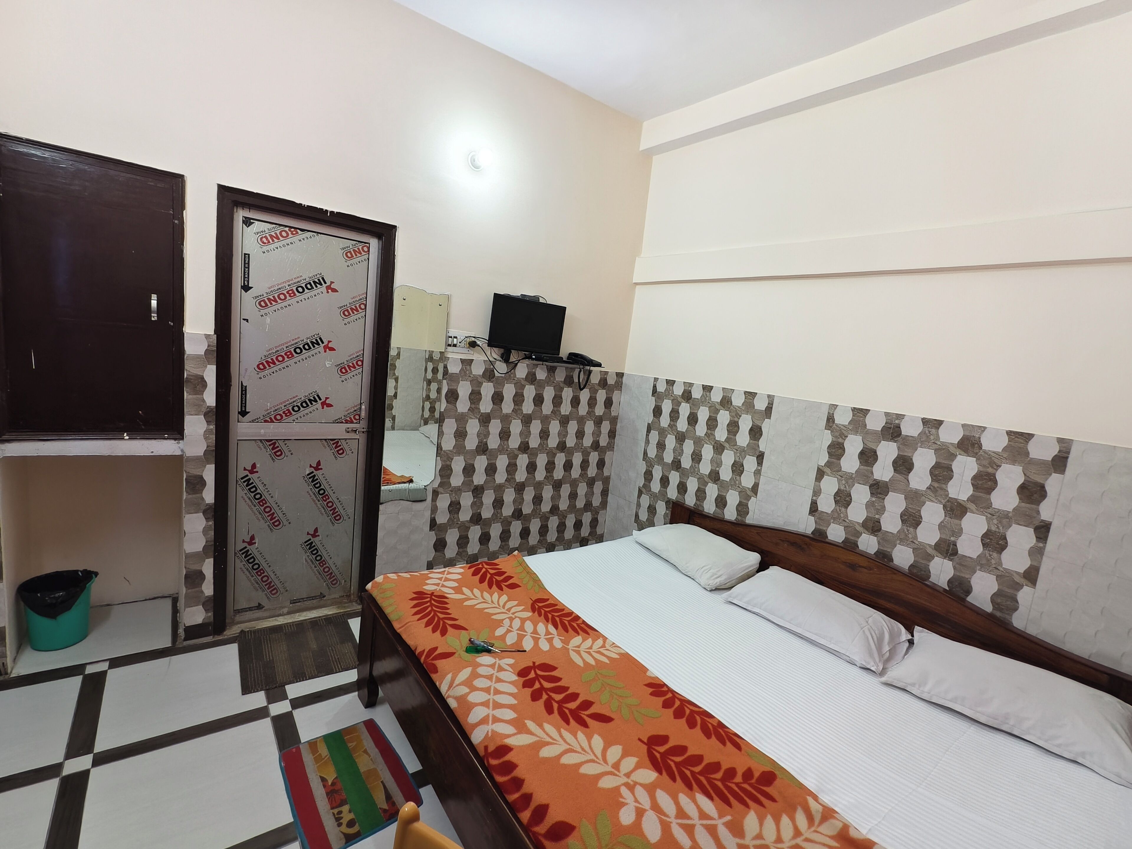 Un dormitorio con cama, armario, televisor y pared con diseño.