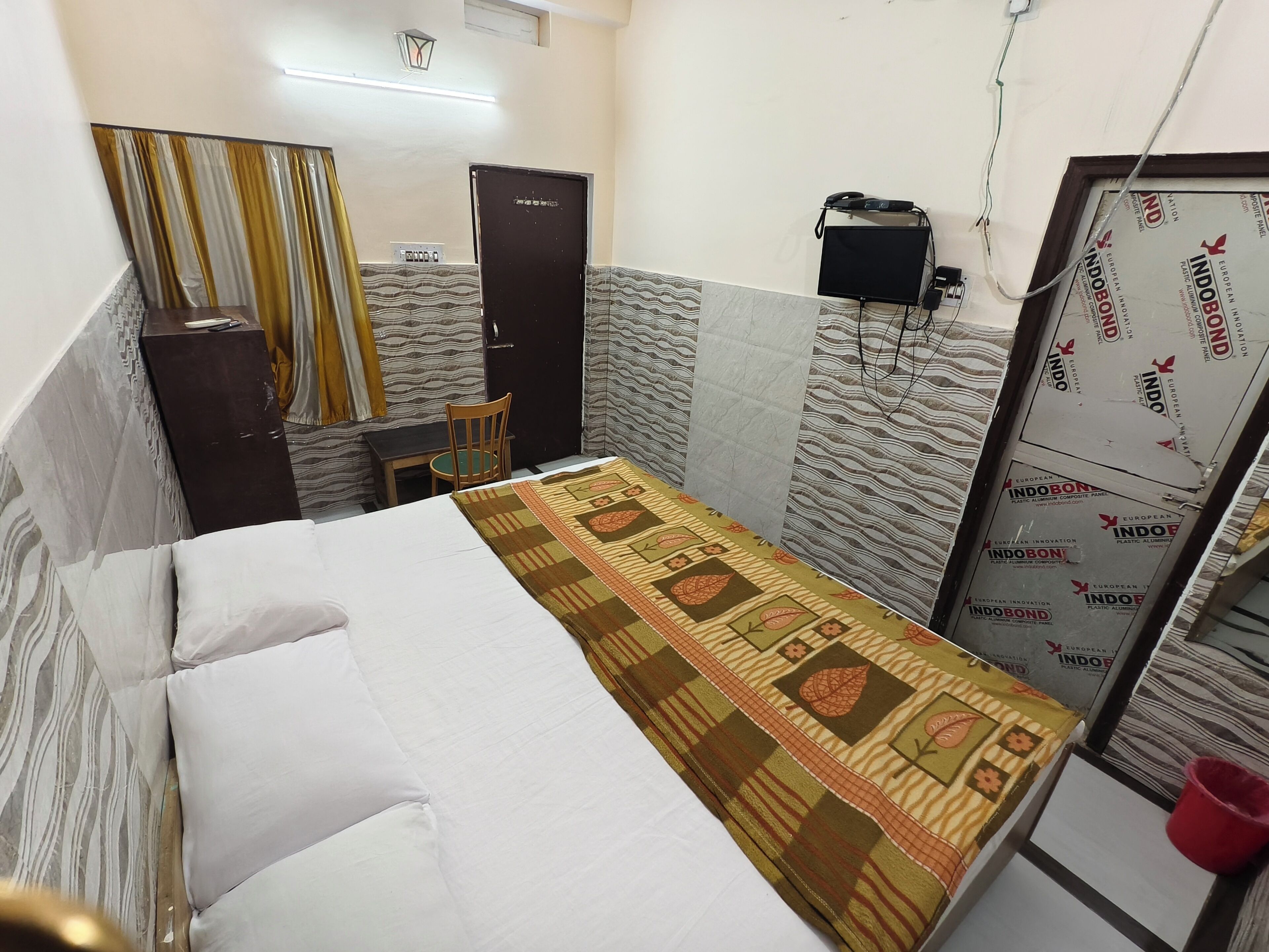 A small, compact room with a bed, a chair, a desk, and a wardrobe.