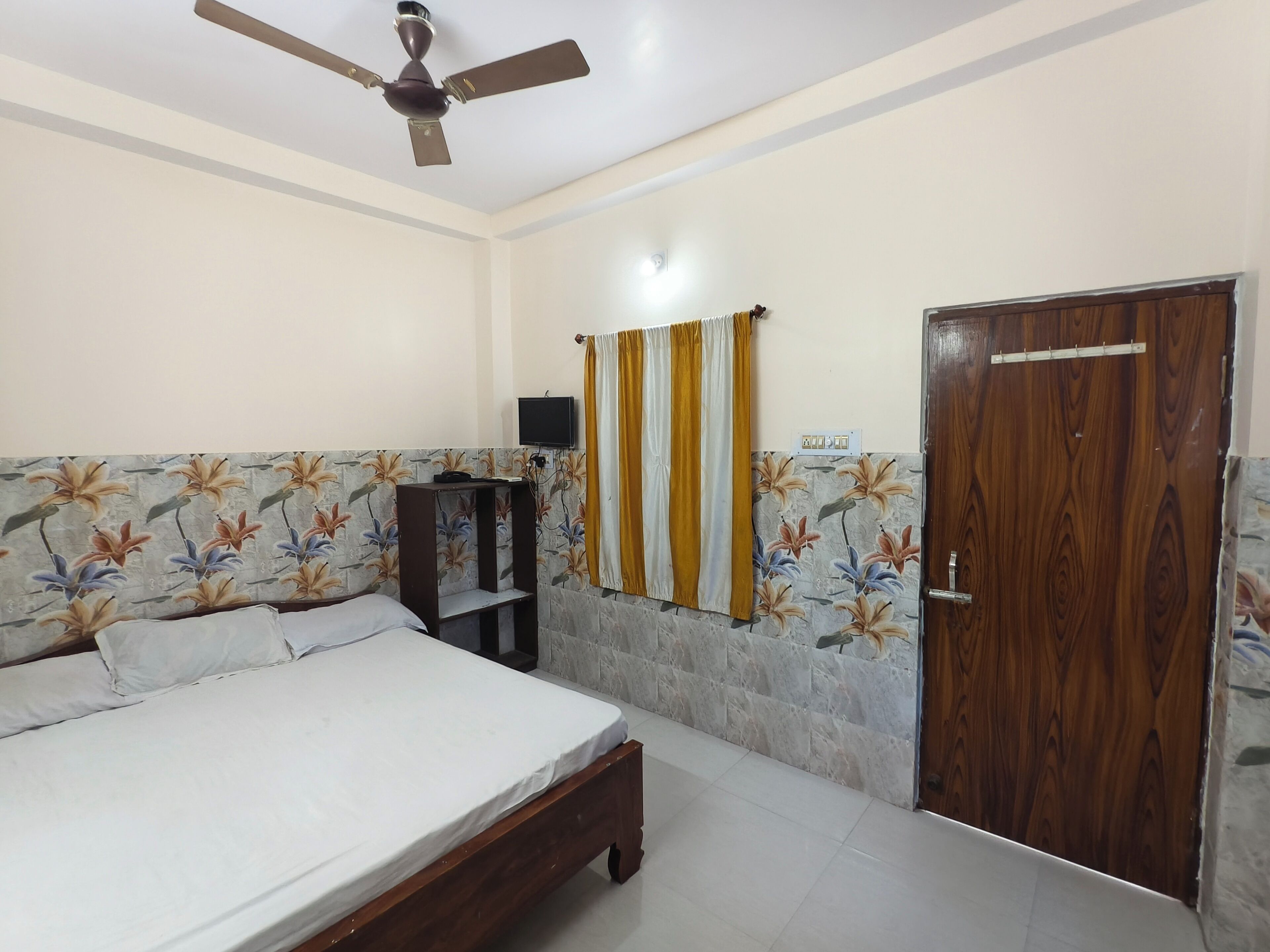 A bedroom with a bed, a ceiling fan, a wardrobe, and a door.
