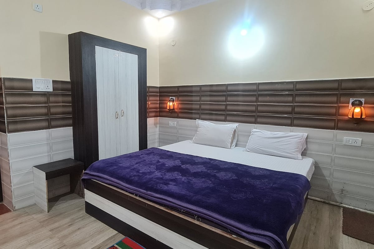 Quarto com cama, mesas de cabeceira, guarda-roupa e luzes na parede.