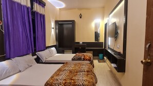 A hotel room with two beds, a TV, a mirror, and a door with star-patterned glass. - Hotel Vijay (Rajgir)