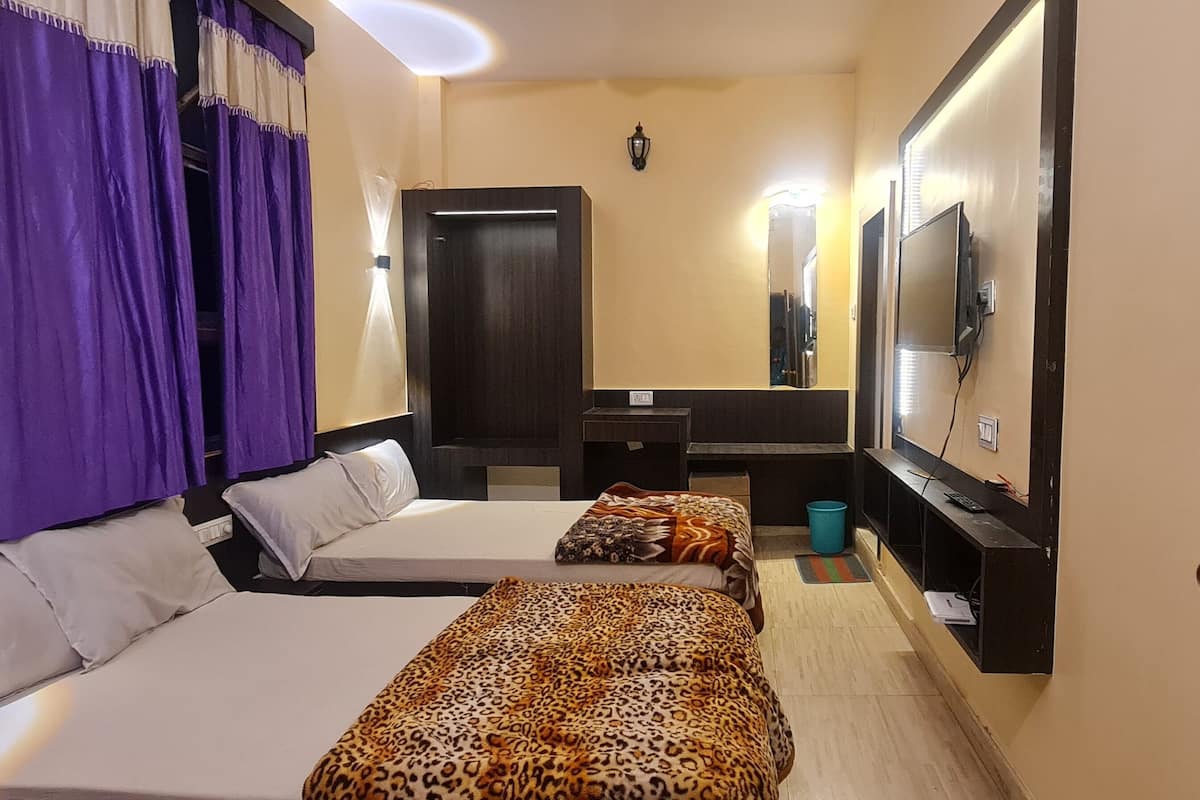 Quarto de hotel com duas camas, uma televisão, um espelho e uma porta com vidro estampado em estrelas.