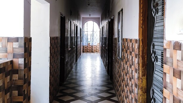 A hallway with patterned flooring and walls, leading to a bright area at the end. - Hotel Vijay (Rajgir)