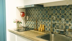 A kitchen with a tiled backsplash, a stainless steel sink, and a countertop with a vase of flowers. - Sweetheart in Saigon - 5mins to the Notre Dame Saigon (Thành phố Hồ Chí Minh)