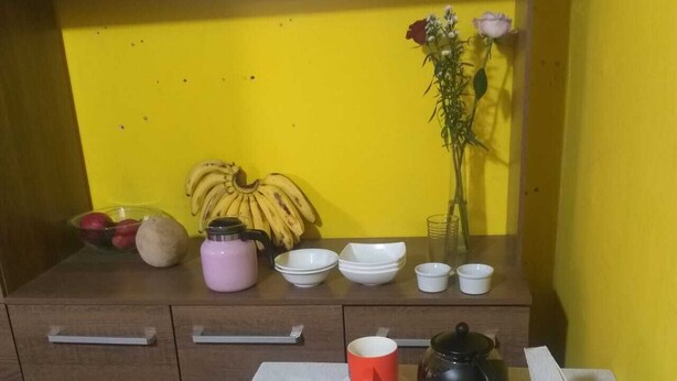 A breakfast table with various food items, a vase with flowers, and a yellow wall in the background. - Hostal Downtown Quito (Quito)