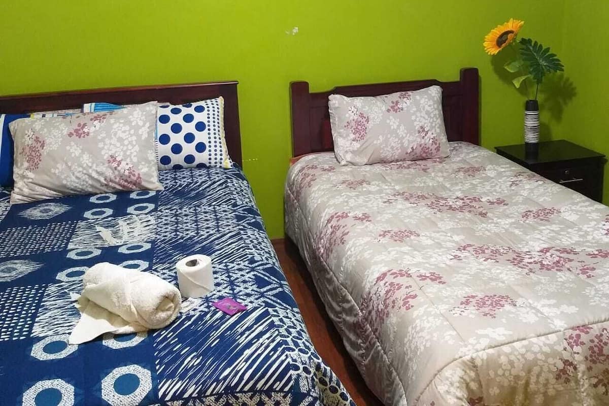 A room with two beds, a green wall, and a framed picture above the left bed.