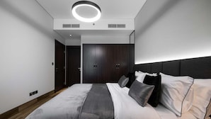 Un dormitorio moderno con una cama grande, un armario de madera oscura y una lámpara de techo circular.