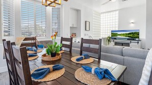 Ein modernes Wohnzimmer mit Essbereich, großen Fenstern und einem Deckenventilator.