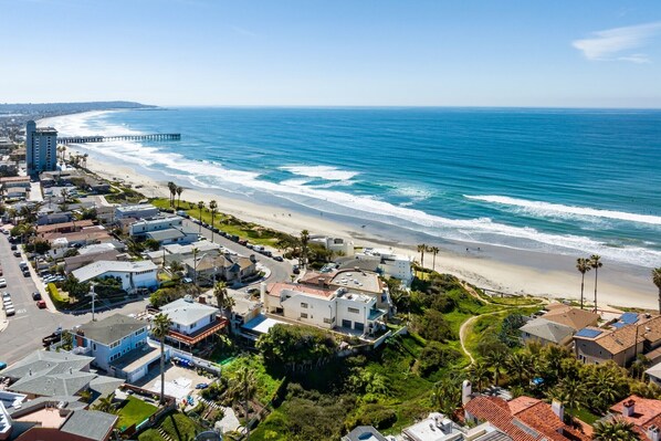 A coastal residential area with beachfront properties, a pier, and a clear blue sky.