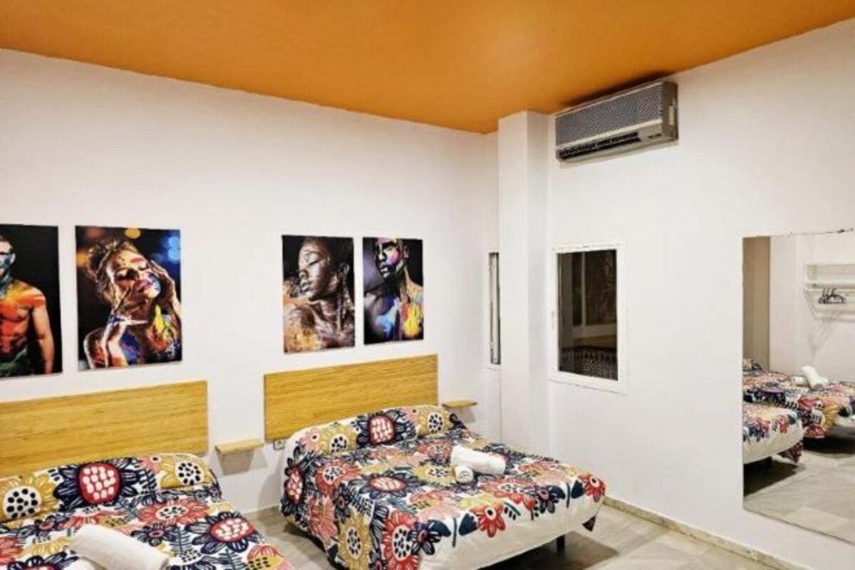 A bedroom with two beds, a wooden headboard, a window, and wall art.