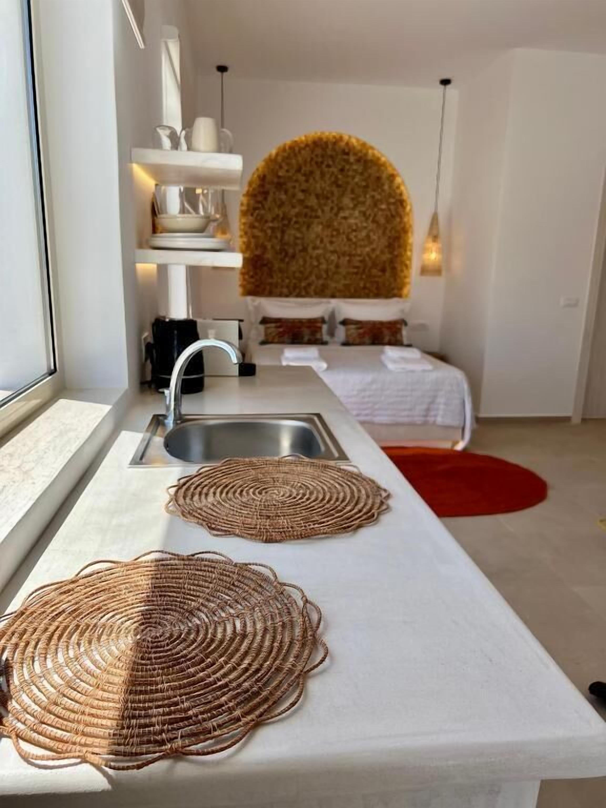 A modern kitchen with a white countertop, two woven placemats, a sink, and a red rug.