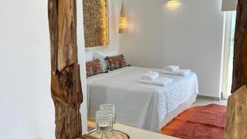 Un dormitorio con un espejo grande, una cama con cubrecama blanco, una lámpara colgante y una alfombra roja.